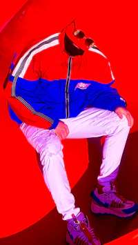 Full-body fashion portrait of independent music artist Nevv Evve standing in a cinematic red environment wearing alternative streetwear and designer sneakers.