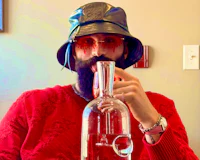 Alternative pop artist Nevv Evve wearing a red Balenciaga sweater, Loewe designer bucket hat, and artistic red sunglasses during a creative lifestyle conversation.