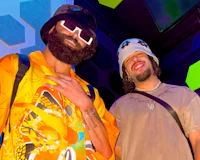 Nevv Evve with his Prada bucket hat and designer shirt collaborating with producer 2eUce2 with his designer bucket hat inside a luxury recording studio during an immersive custom music creation and songwriting experience.