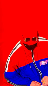 Close-up portrait of alternative pop artist Nevv Evve wearing a red and blue vintage jacket and gold sunglasses against a vivid red background.