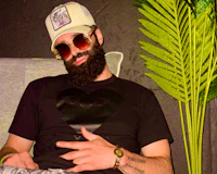 Nevv Evve relaxing in a modern artistic podcast studio wearing designer sunglasses and a Comme des Garcons PLAY t-shirt during live creative and luxury lifestyle podcast.